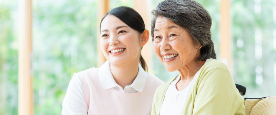 介護職員と高齢入居者が窓辺で楽しく会話している生活風景